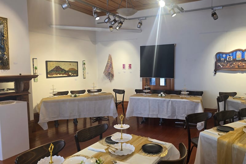 A gallery room at Lake House Arts Centre set with long tables, gold runners and cake stands for a high tea